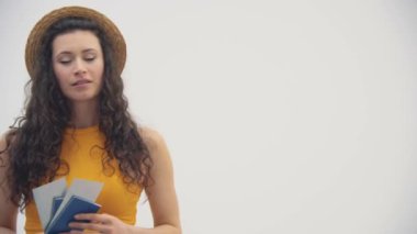 Pasaportu ve bileti elinde tutan güzel bir kızın beyaz arka planda 4K videosu..