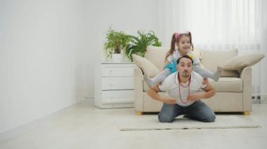 Babası yerde oturuyor, küçük kızı da omuzlarında ayrı bir pozisyonda.