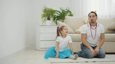 Güzel kız bölünüyor. Babası da aynı şeyi yapmaya çalışıyor, ama doğru düzgün esneyemiyor. Kızı ona gülüyor..