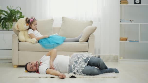 Mała wróżka machająca magiczną różdżką i wyczarowująca ojca w balerinach na podłodze. — Wideo stockowe