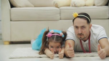 Canlı baba ve kızının yerde yatıp baş parmaklarını kaldırarak bedenlerini sanki bir aracı sürüyormuş gibi bir yandan diğer yana hareket ettirmesi..