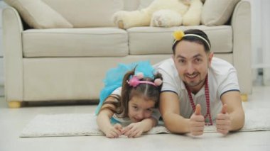 Hayat dolu baba kızıyla oynuyor, yerde yatıyor, ona baş parmağını kaldırmayı öğretiyor..