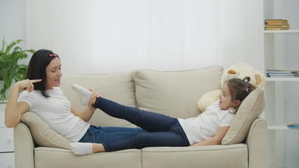 4k wideo matki i córki leżących na białej kanapie. — Wideo stockowe