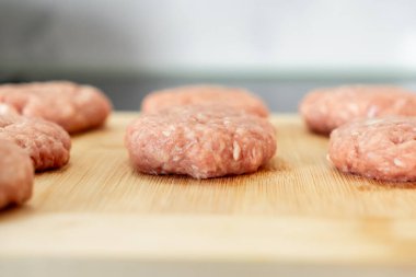 Açık renkli bambu kesme tahtasının üzerinde dinlenen birkaç taze çiğ pirzola yakın plan, sağlıklı, besleyici ev yapımı yemek için hazırlıkları vurguluyor