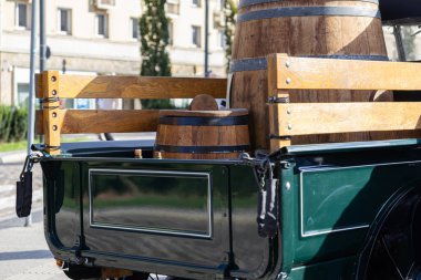 Klasik koyu yeşil kamyonet yatağının arka planında ahşap korkuluklar ve iki eski ahşap varil var. Bu da geleneksel kargo teslimatı ve tarihi ticaret olduğunu gösteriyor.