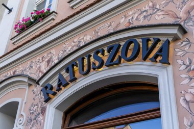 Poznan, Polonya - 31 Ağustos 2025: Aydınlık bir işaret olan Ratuszova, süslü freskler ve canlı pembe çiçekler sergilenen antik bir Avrupa binasını vurguluyor