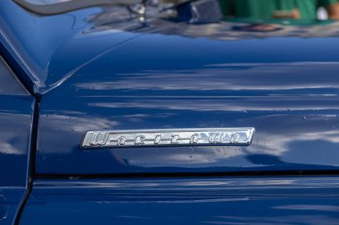 Poznan, Polonya - 31 Ağustos 2025: Parlak krom Warszawa amblemi, Polonya otomotiv mühendisliğinin tarihsel önemini vurgulayarak klasik koyu mavi araba gövdesini süslüyor