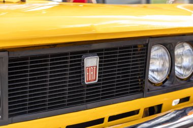 Poznan, Polonya - 31 Ağustos 2025: Frontal yakın plan, parlak sarı klasik bir arabanın koyu renkli ızgarasının merkezindeki ikonik Polski Fiat amblemini yakaladı