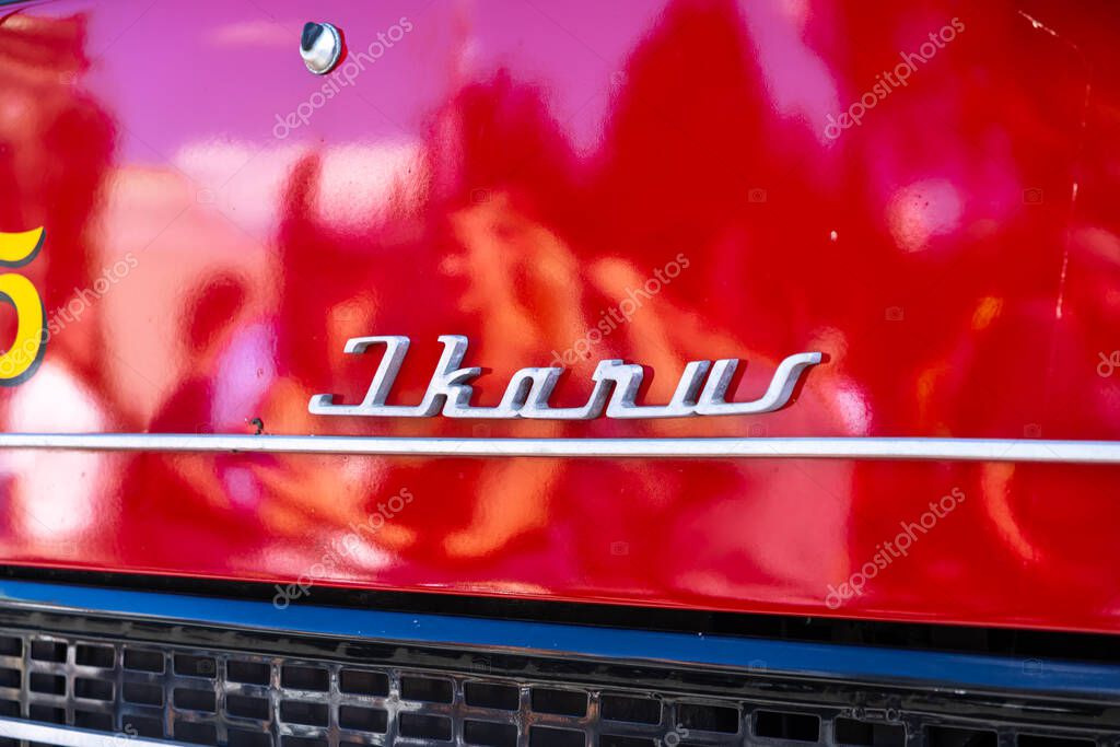 Poznan, Poland - August 31, 2025: Close-up details the Ikarus metallic emblem on weathered red paint, reflecting its public transport history