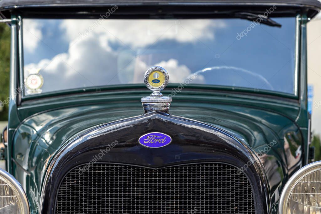 Poznan, Poland - August 31, 2025: Close-up of a Ford classic vintage car's dark green front grille with its iconic blue logo and a shiny radiator cap
