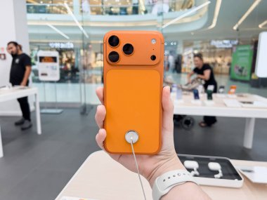 Poznan, Polonya - 20 Eylül 2025: iPhone 17 Pro cihaz portakal kapaklı, elinde sergilenen, hareketli modern bir alışveriş merkezinde yeni bir teknoloji vurguluyor