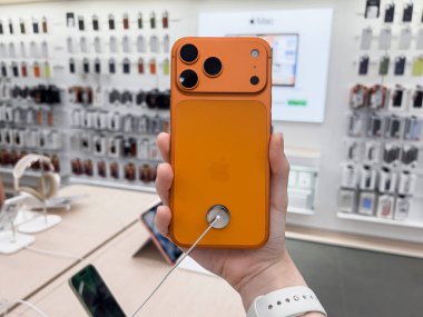 Poznan, Polonya - 20 Eylül 2025: Bir Apple perakende mağazasında üç kameralı yeni bir akıllı telefon modeli olan turuncu iPhone 17 Pro 'yu elinde tutan kişi