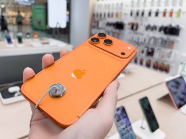 Poznan, Polonya - 20 Eylül 2025: Bir el bir elektronik mağazasında turuncu bir iPhone 17 Pro 'yu güvenli bir şekilde tutuyor, yenilikçi tasarım ve tüketici ilgisini vurguluyor