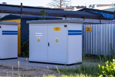 Poznan, Polonya - 20 Eylül 2025: Çağdaş endüstriyel ortamlarda enerji yönetimi için hayati önem taşıyan görünür tehlike işaretleriyle dolu, sağlam gri elektrikli anahtar dolabı açık havada duruyor