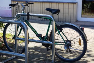 Poznan, Polonya - 20 Eylül 2025: Canlı, krom kaplı yeşil bir bisikletin yan görüntüsü, güneşli bir günde bina yakınında güvenli bir şekilde park edilmiş, çevre dostu kentsel dönüşümü destekliyor