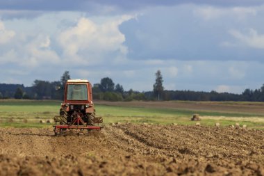 Tarladaki bir traktör toprağı gevşetir..