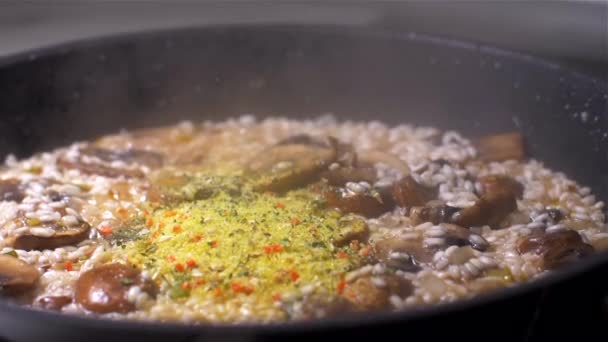 Cozinhar risoto com cogumelos e adicionar caldo seco em pó. Movimento lento — Vídeo de Stock