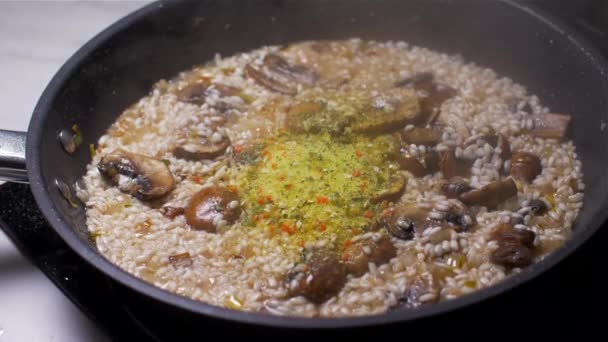 Cozinhar risoto com cogumelos e adicionar caldo seco em pó. Movimento lento — Vídeo de Stock