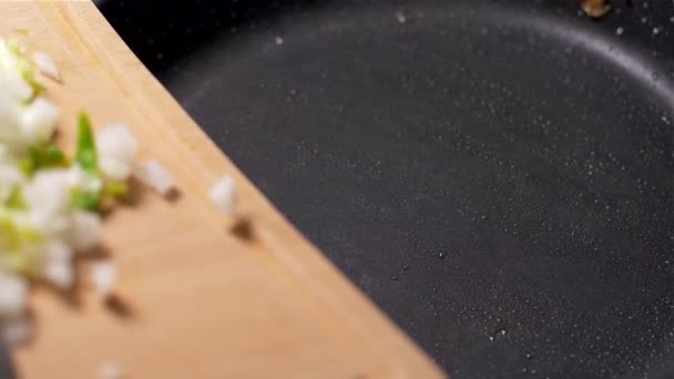 Closeup of  hands putting chopped onion on hot frying pan — Stock Video