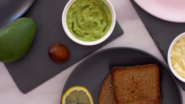 Café da manhã saudável com sanduíche de abacate e salada de ovo vista superior — Vídeo de Stock