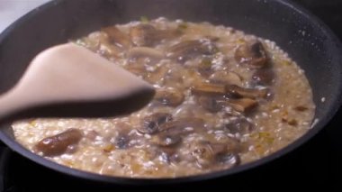 Şef bir tavada mantar ile risotto atar