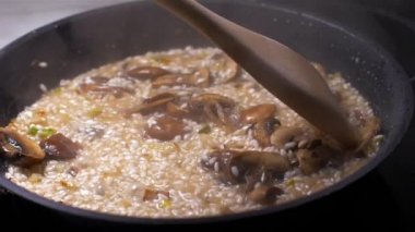 Şef bir tavada mantar ile risotto atar