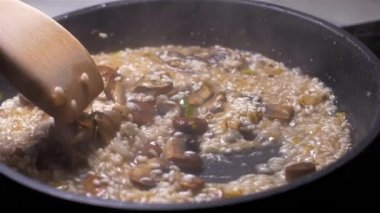 Şef bir tavada mantar ile risotto atar