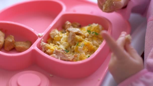 Ett barn äter en silikon maträtt med händerna — Stockvideo