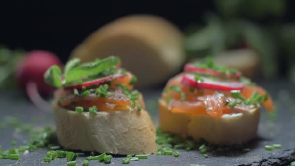 Sabrosos sándwiches de salmón sobre fondo negro. Movimiento lento — Vídeo de stock