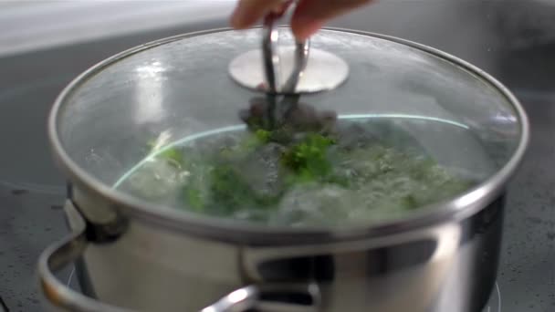 Lifting the lid of the pan with boiling water and broccoli. slow motion — Stock Video