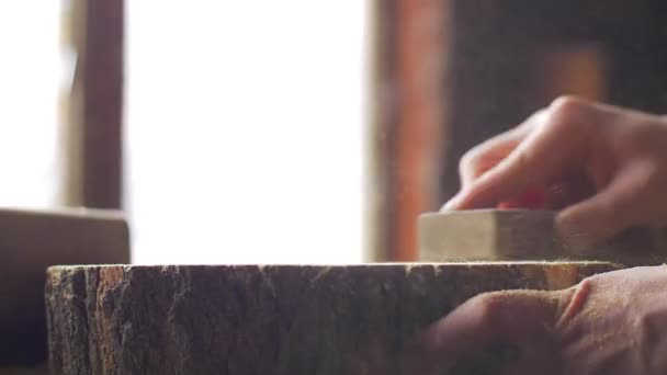 Le charpentier polit la planche en bois avec le papier de verre sur le bureau. — Video