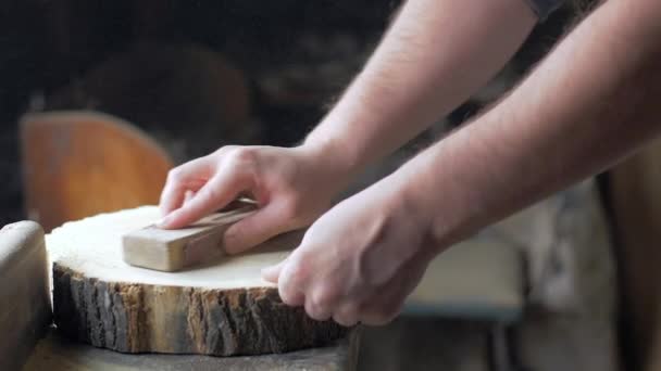 Le charpentier polit la planche en bois avec le papier de verre sur le bureau. — Video