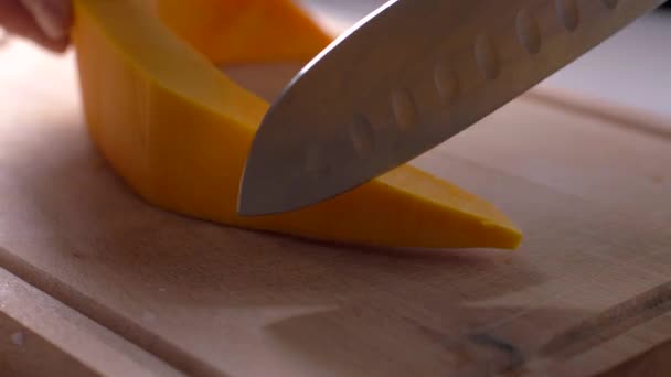 Cut a pumpkin with a knife on a wooden board — Stock Video