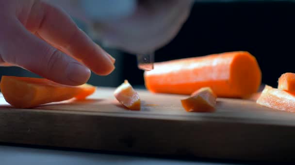 Het snijden van wortelen op een houten plank. tegen licht. Slow Motion — Stockvideo