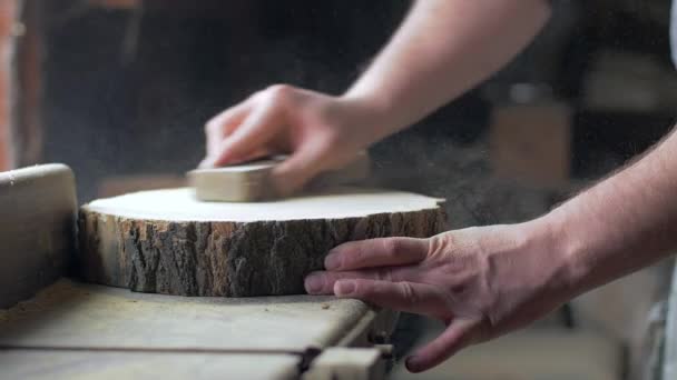 Le charpentier polit la planche en bois avec le papier de verre sur le bureau. — Video