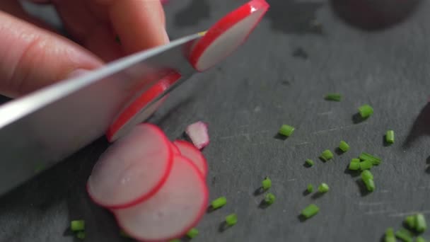 Het snijden van radijs op zwarte steen. Slow Motion — Stockvideo