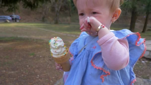 Porträt eines kleinen blonden Mädchens, das im Park Eis isst. Zeitlupe — Stockvideo