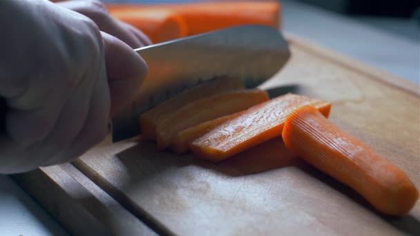 Het snijden van wortelen op een houten plank. tegen licht. Slow Motion — Stockvideo