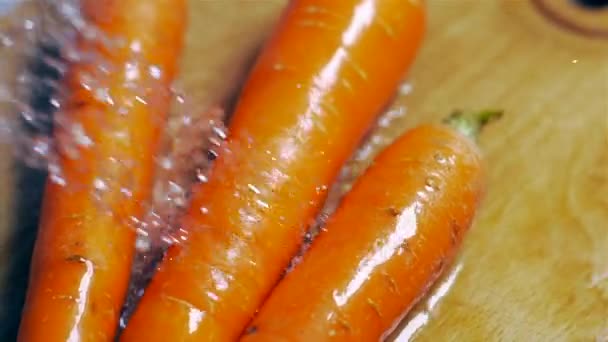 Het wassen van verse wortelen op een houten plank in een slow motion — Stockvideo