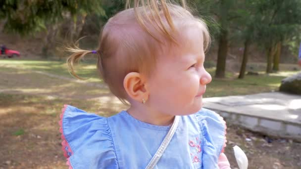 公園でアイスクリームを食べている小さなブロンドの女の子の肖像画。スローモーション — ストック動画