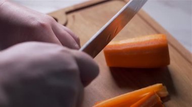 Tahta bir tahtada havuç kesmek. karşı ışık. Yavaş çekim