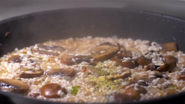 Chef lança o risoto com cogumelos em uma panela — Vídeo de Stock