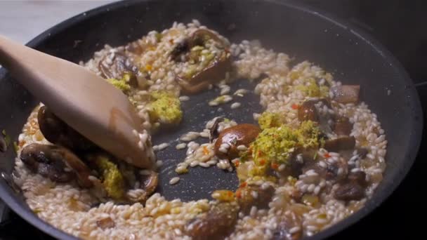 Risotto mit Champignons kochen und trockenes Brühpulver hinzufügen. Zeitlupe — Stockvideo