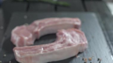Kemikli çiğ domuz pirzolası. Biberiye çiğ ete düşüyor.