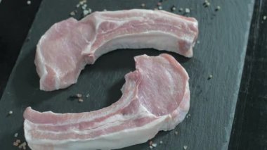 Kemikli çiğ domuz pirzolası. Biberiye çiğ ete düşüyor.