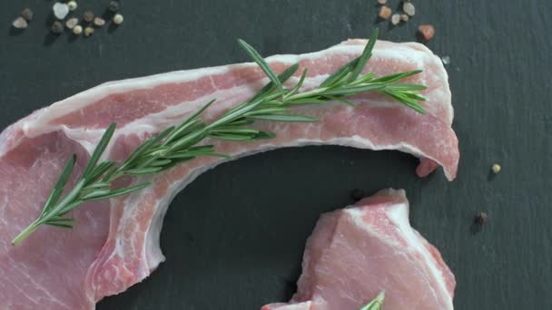 Côtelettes de porc crues avec os. Romarin tombe sur la viande crue . — Video