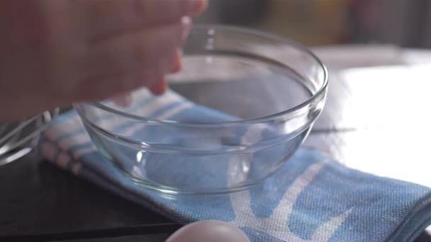 Разбивание яиц в стеклянную миску — стоковое видео