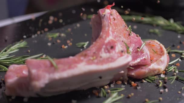 Chuletas de cerdo crudas con especias caen una sobre la otra — Vídeo de stock