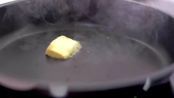 요리사가 가열 된 팬에 버터 큐브를 넣습니다. — 비디오