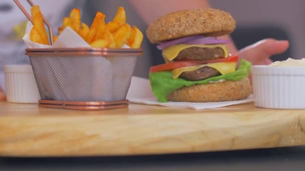 Sirve cerveza y jugosa hamburguesa americana con papas fritas. Movimiento lento — Vídeo de stock